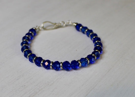 Blue beaded bracelet with silver clasp on a light gray background