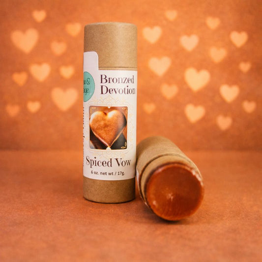 Spiced Vow product with bronzed devotion label on an orange background with heart shapes.