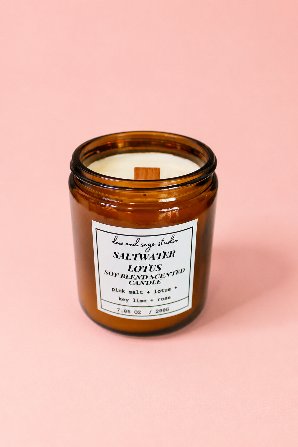 Amber glass candle with a label on a pink background