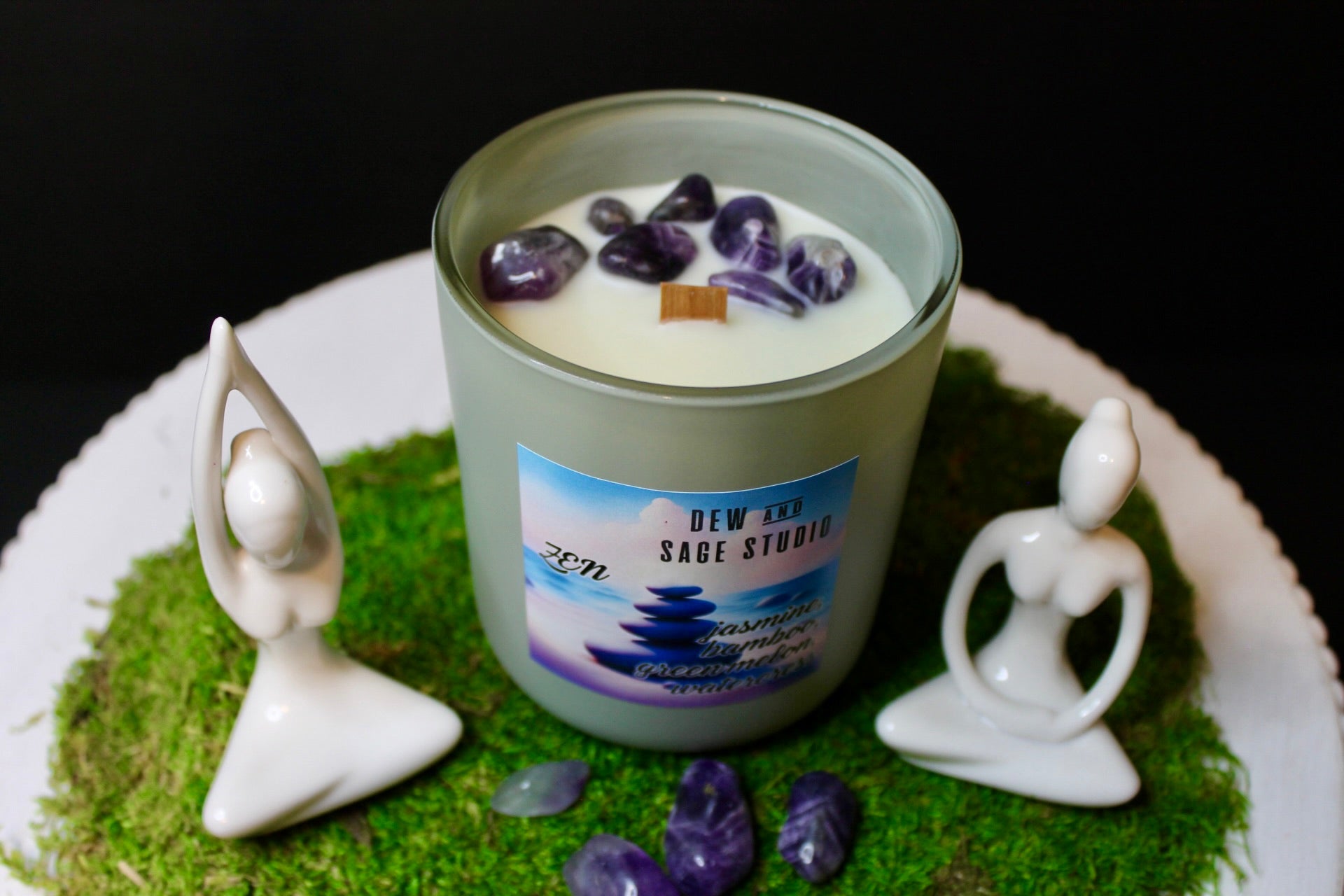 Candle with amethyst stones on a green base with statues and moss
