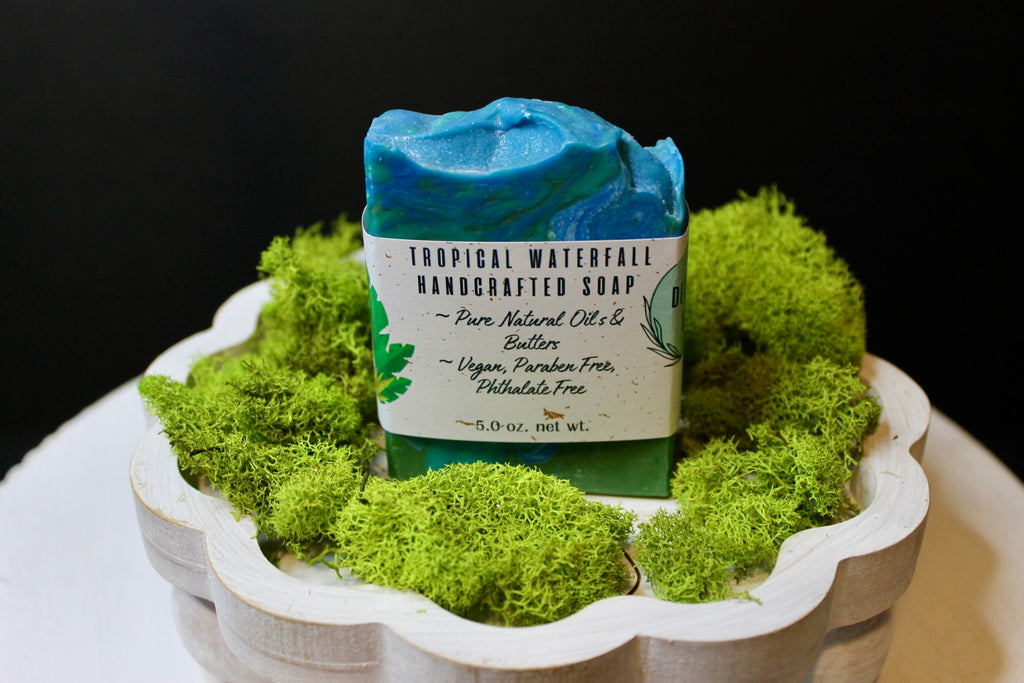 Handcrafted soap bar with a label on a bed of green moss in a decorative bowl.