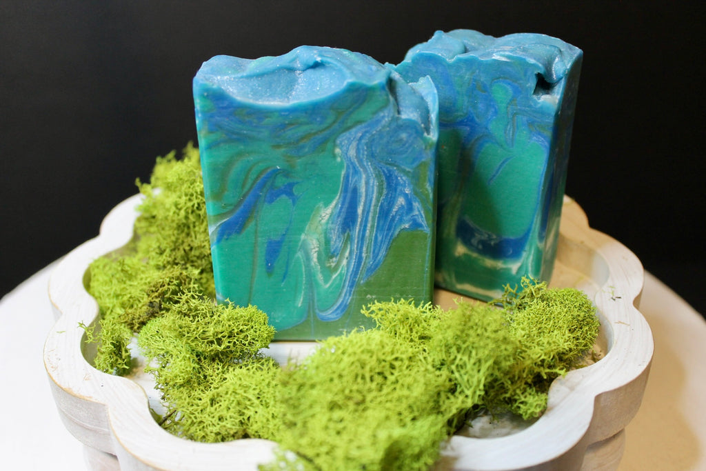 Two blue and green marbled soap bars on a bed of green moss.