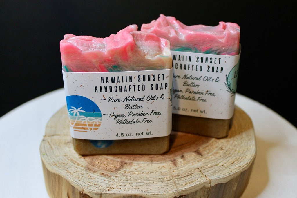 Two handcrafted soaps on a wooden block with visible labels.