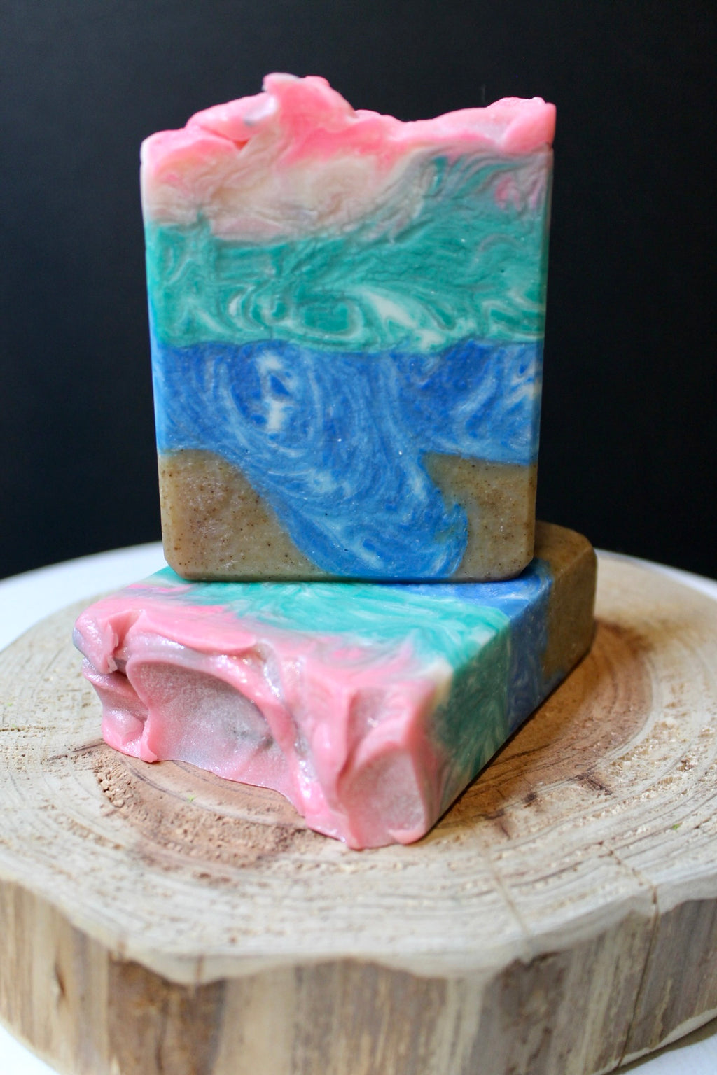 Colorful ocean layered soap bar on a wooden surface with a dark background