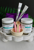 Cosmetic products including jars, brushes, and a bowl on a wooden stand with a dark background.