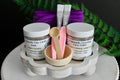 Cosmetic set with jars labeled 'Chamomile Clay Facial Mask' and 'Chamomile Cleansing Face Polish' on a white stand.
