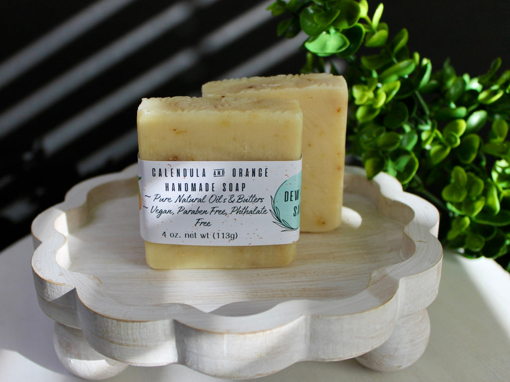 Two bars of soap on a decorative stand with a plant in the background