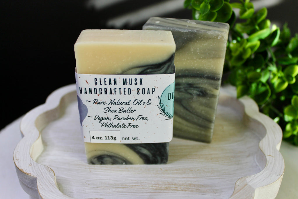 Handcrafted soap bars on a wooden stand with greenery in the background