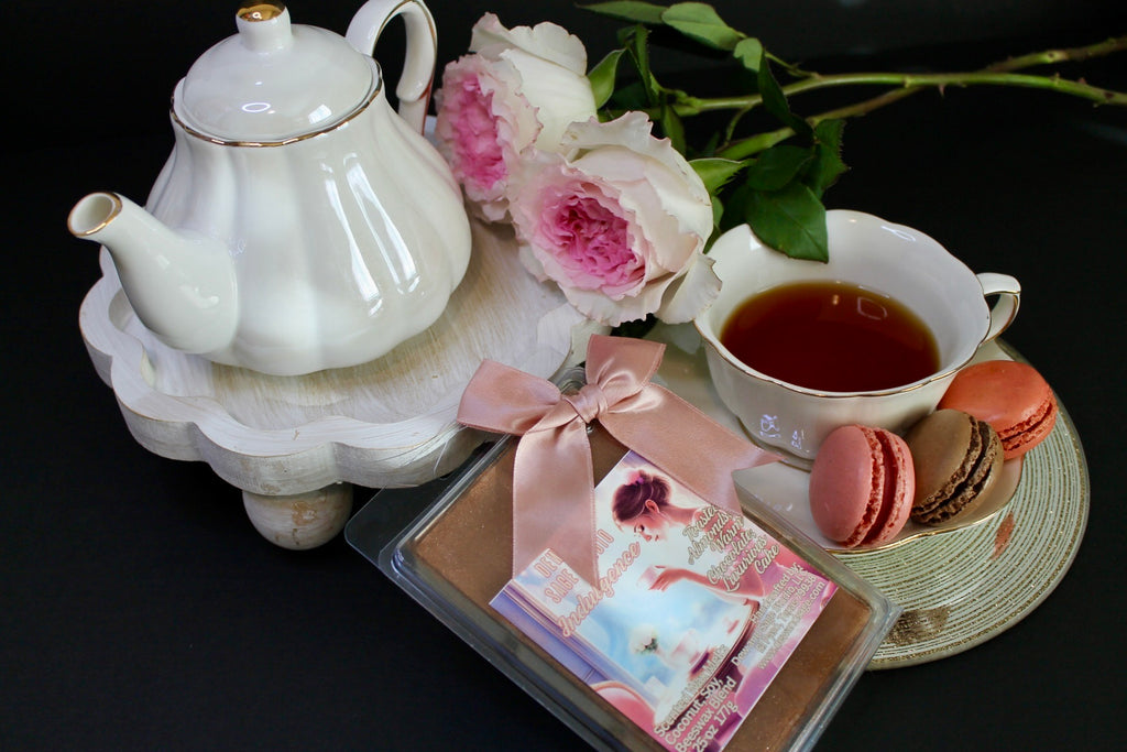 Tea set with teapot, cup, cookies, wax melts and flowers on a dark background