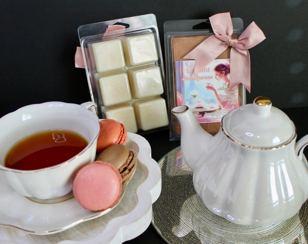 Tea set with a teapot, cup, wax melts and cookies on a reflective surface.