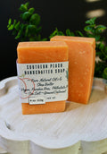 Two bars of Southern Peach Handcrafted Soap on a white surface with a green plant in the background.