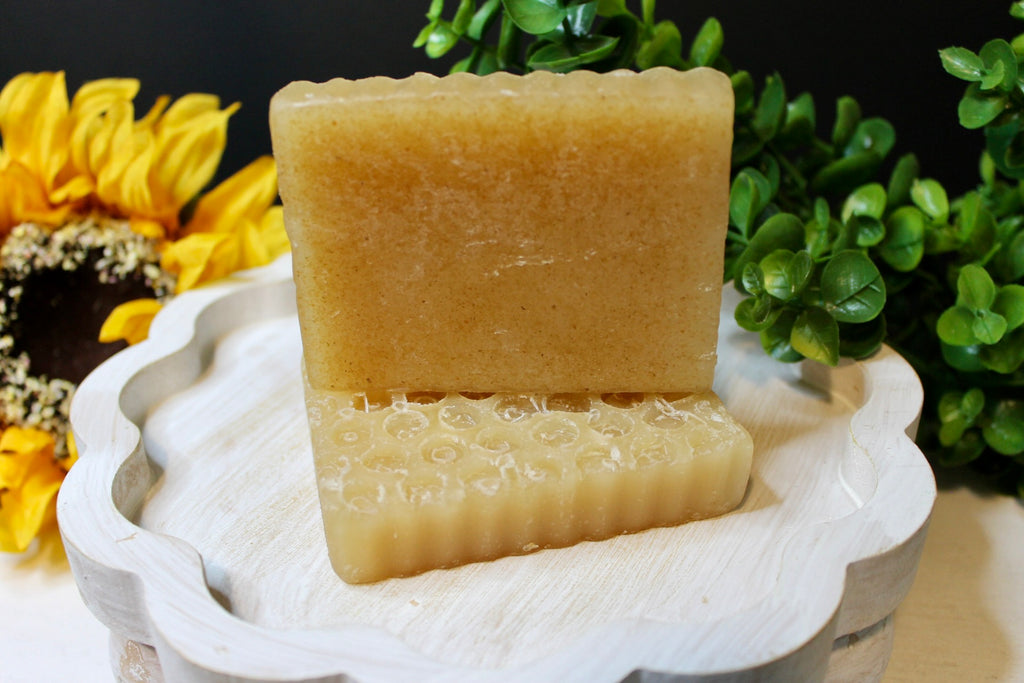 Bar of soap on a white dish with greenery and sunflowers in the background