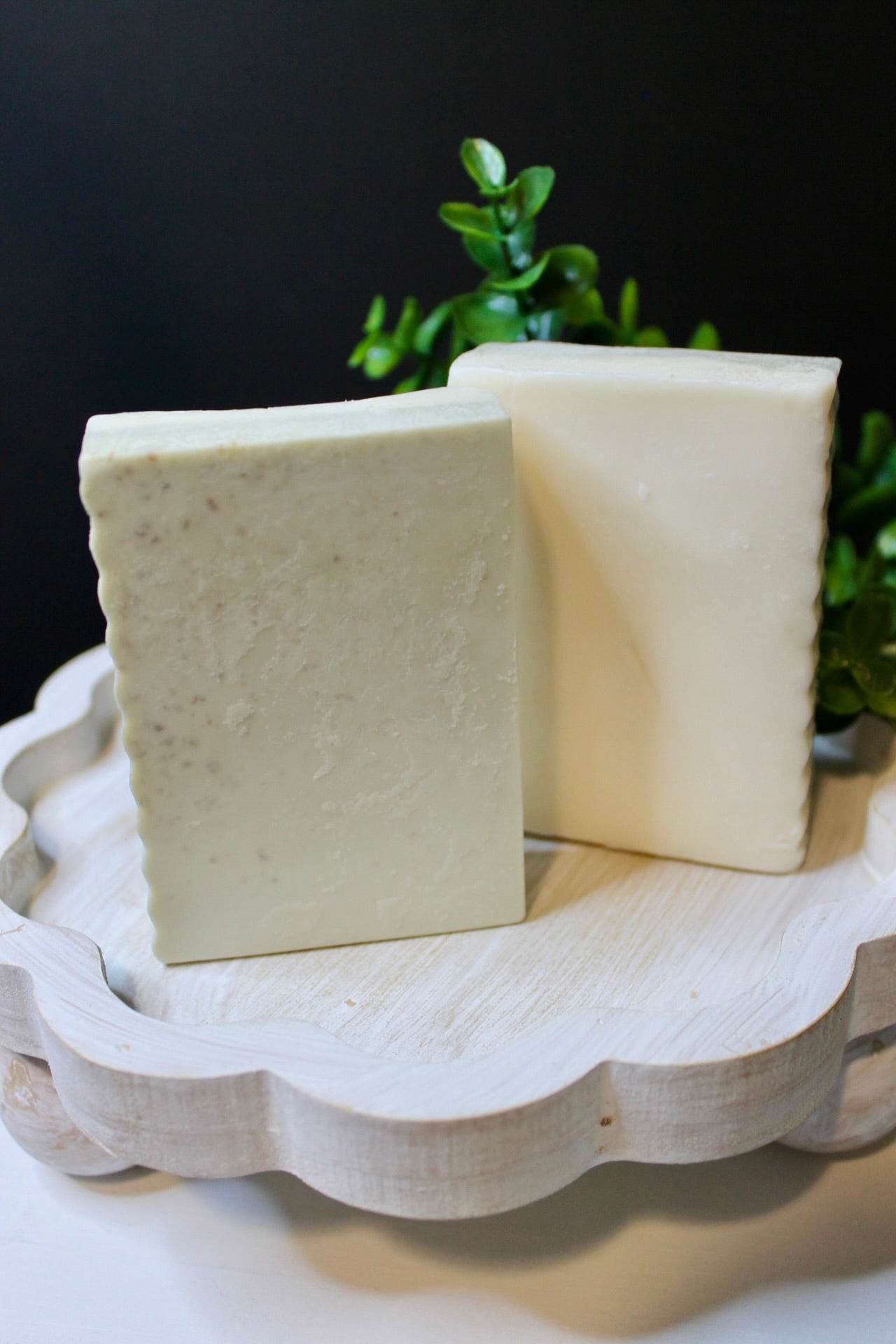 Two bars of soap on a decorative stand with a dark background