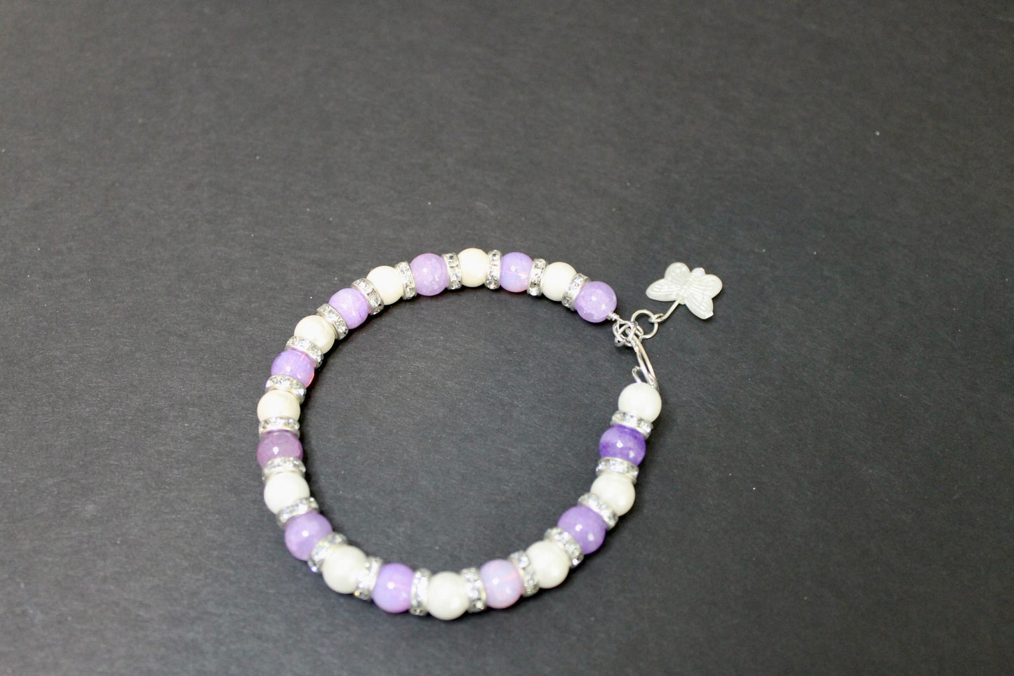 Beaded bracelet with purple and white beads on a dark gray background