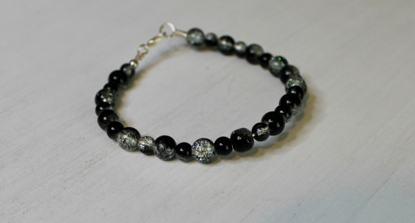 Black beaded bracelet with silver accents on a white background