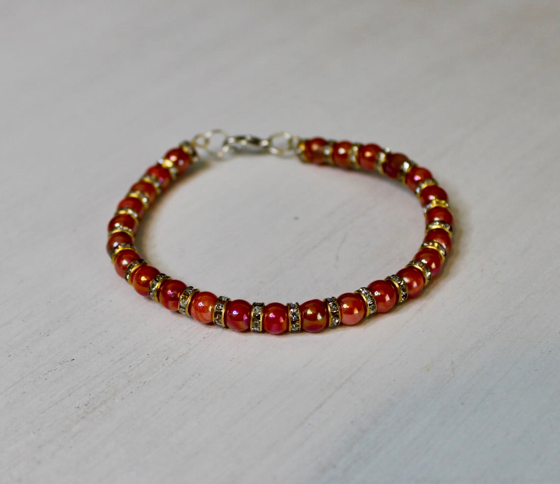 Beaded bracelet with red and gold beads on a light gray background