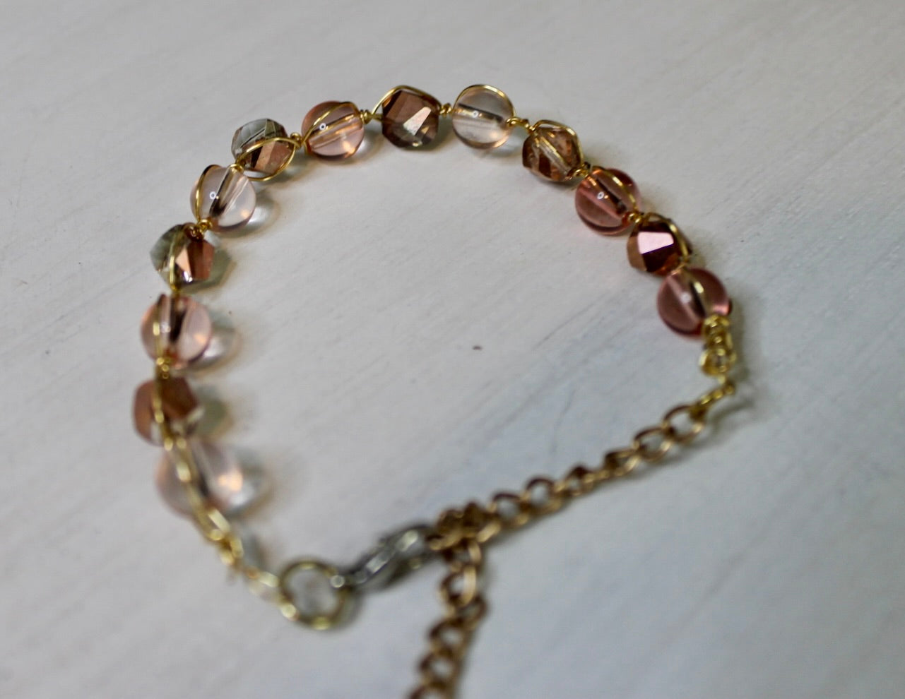 Bracelet with multicolored beads and gold chain on a light gray background