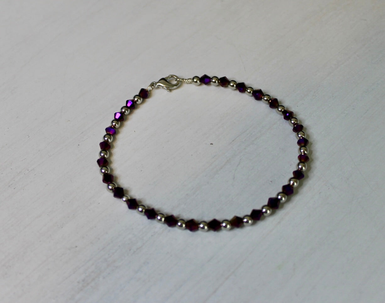 Beaded bracelet with purple and silver beads on a white background