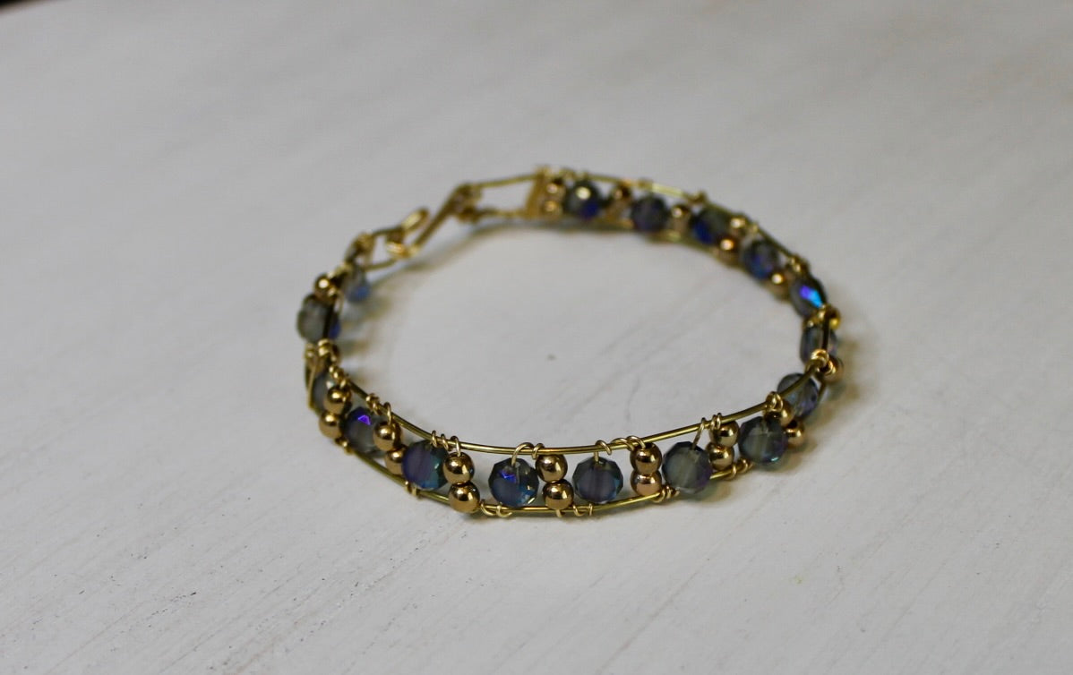 Gold bracelet with blue stones on a white background